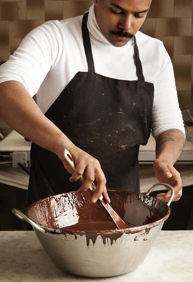professional-chief-black-man-twist-tasty-melted-chocolate-big-steel-pot-before-making-chocolate-bars 1